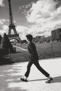 Young man, walk, Eiffel Tower, park, clouds, grass, fence.